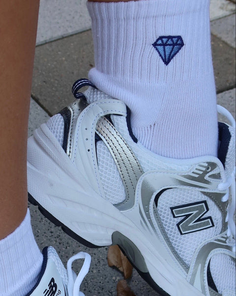 White socks with a blue diamond design on a pavement background.