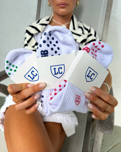 Person holding three pairs of socks with visible brand logos.